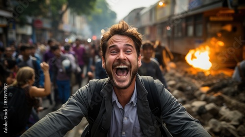 A joyous man celebrates openly in the foreground of a blurred, chaotic protest scene with fire and crowds