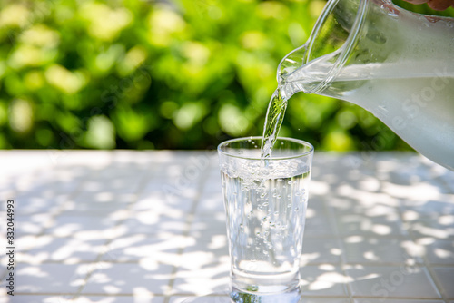 水を注ぐ 木陰のテーブルで冷たいミネラルウォーターを飲む