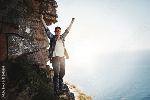 Man, mountain and celebration for excited, hike and top peak for exercise in nature on weekend. Sunrise, sports and outdoor adventure for active male person, explore and climbing for workout fitness