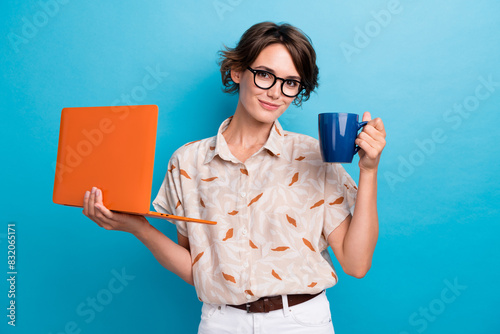 Portrait of successful pretty girl hold laptop fresh coffee mug isolated on blue color background