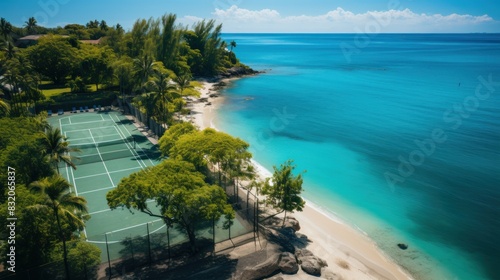 Overhead view of a lush tropical beach resort featuring a tennis court beside the clear blue sea