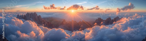 Ethereal view of sun rays piercing through fluffy clouds at dawn, highlighting the peaks of rugged mountains below