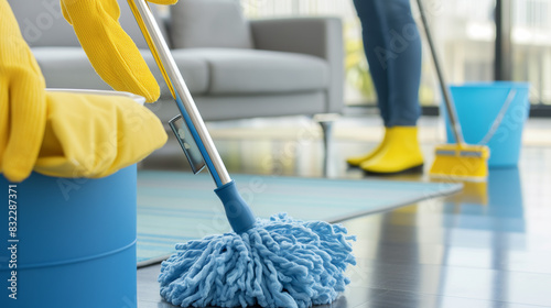 A woman is cleaning a floor with a blue mop. The mop is blue and has a yellow handle