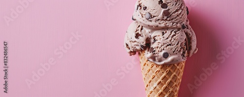 Mocha chip ice cream in a sugar cone on a vibrant pink background, rich and indulgent