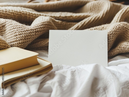 A blank card on a cozy bed with a warm blanket and a book nearby. The comfortable setting is perfect for personal messages or lifestyle branding.