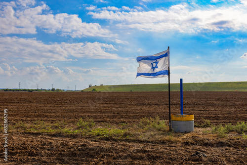 Israeli flag stands in the middle of a field somewhere in the center of the country