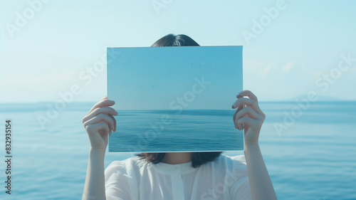 海の景色を映す鏡を持つ日本の若い女性