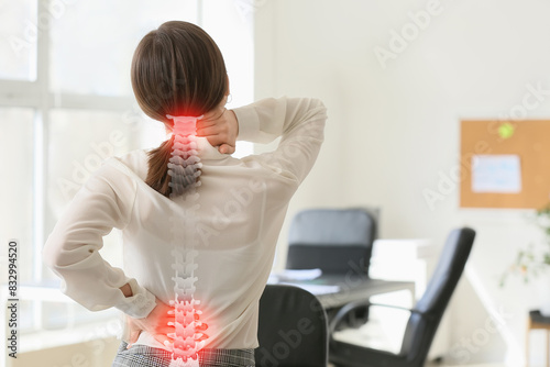 Young businesswoman suffering from back pain in office