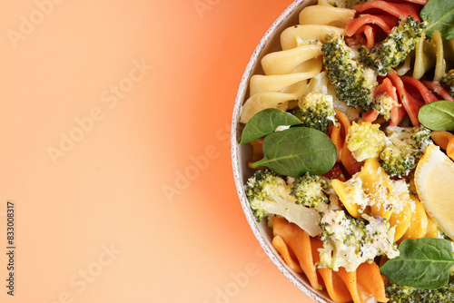 Delicious fusilli pasta with broccoli and lemon piece in bowl on beige background, closeup