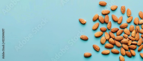Top view of a handful of almonds scattered randomly on a light blue isolated background, natural studio lighting highlighting their details