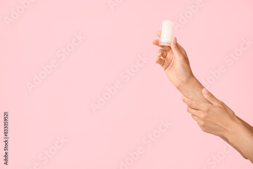 Female hands with deodorant on pink background
