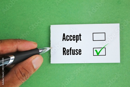 hand holding pen and white paper with two word options Accept or refuse? Refuse