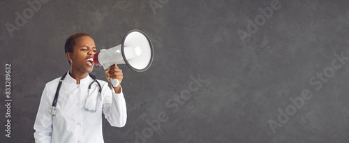 Medical announcement. African American female healthcare worker loudly announces information using a loudspeaker. Concept of medical marketing and sales. Gray background. Copy space Banner.