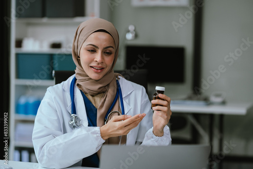Caring muslim therapist conducts video consultation, communicates with patient via an online conference, uses laptop, diagnoses, recommended and prescribed medications, and also answers questions.