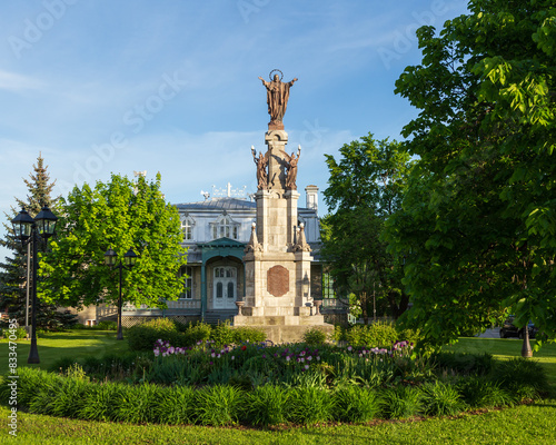 Spring afternoon view of the 1861 Sacred Heart monument in front of the 1887 presbytery with its metal mansard roof and ornate railing, Saint-Augustin-de-Desmaures, Quebec, Canada