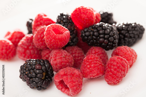 Handful of raspberry and blackberry berries on white background