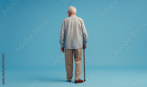 Elderly Man Walking Away with Cane on Plain Background, viewed from behind, isolated on a blue background with ample copy space.