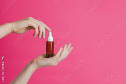 Serum brown glass bottle or essential oil with pipette on pink background. Natural Organic Spa Cosmetic concept