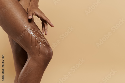 A pretty, slim African American woman with legs covered in coffee scrub