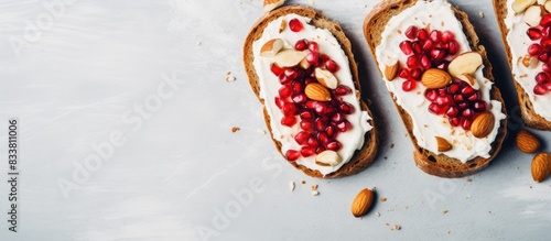 Healthy open sandwiches on rye bread with cream cheese, pomegranate seeds, and almond flakes on a marble surface for a top view copy space image.