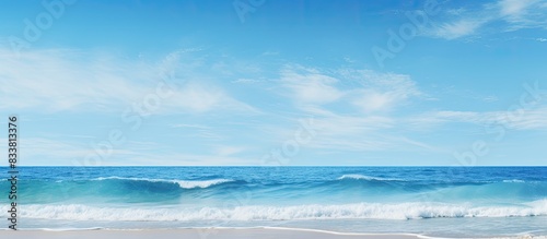 Ocean waves lapping the shore under a clear blue sky, with ample copy space image.