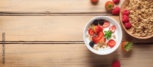 View from above of a bowl of granola topped with strawberries and cashew nuts, along with a breakfast muesli served with milk and berries, both dishes presented with copy space image.