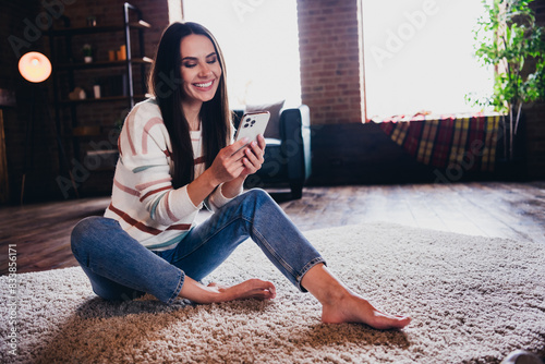 Photo of funny charming lady dressed striped sweater sitting floor communicating modern gadget indoors house room