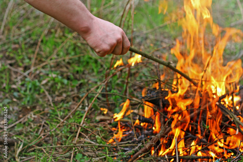 The image of the hand of a man who agitates the coals in the fire.