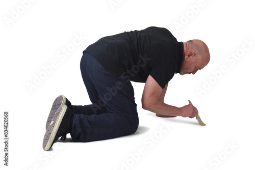  view of a man on knees painting on the floor with a brush on white background