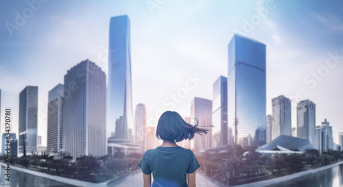 日本の街・都市・朝日を受けたオフィスビル群を前に佇み風を受けて髪をなびかせる会社員の女性の出勤 就職・ビジネス・はじまり・決意・目標・挑戦のイメージ