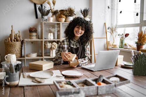 Small business selling goods on the Internet. Entrepreneur sells dishes, plates and cups made of clay, ceramics online and packs them in boxes for sending to the delivery service.