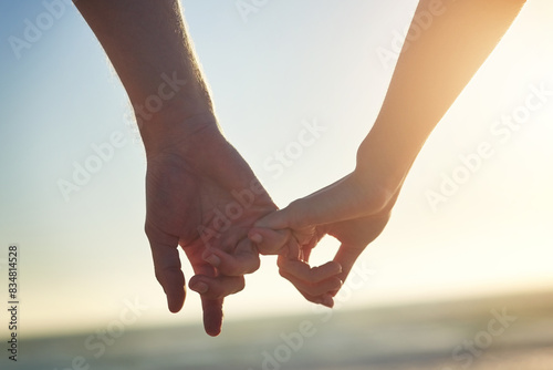 Couple, holding hands and little finger at beach in close up with bonding, love and connection on vacation. People, partner and sunset for trust, care and pinky promise by sea on holiday in Greece