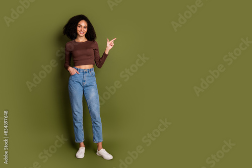 Full size photo of pretty young girl point empty space wear trendy brown outfit isolated on khaki color background