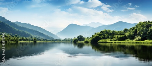 Stock image of a peaceful lake set against a backdrop of lush green mountains with available copy space for text or graphics.