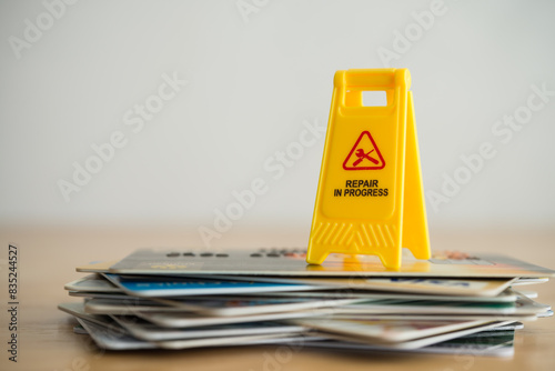 Close up yellow warning sign "Repair in progress"on many credit card white wall background copy space. Past due payment or least minimum for credit card, personal financial problem, bankrupt concept.