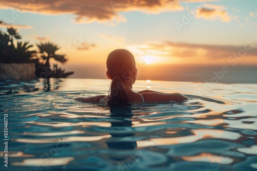 The serene image of a woman swimming in an infinity pool as the sun sets, evoking peace and relaxation