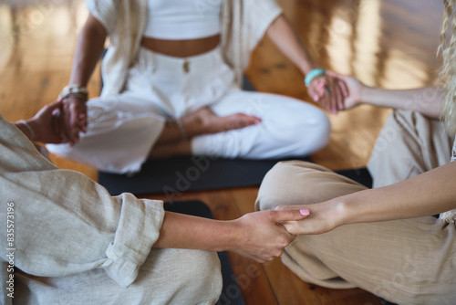 Healthy mindful women group sitting in circle meditating together holding hands doing yoga breathing exercises giving support during body health retreat holistic healing training session. Close up.