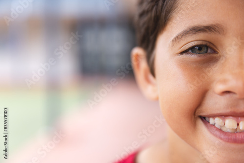 In school outdoors, young biracial male student smiling at camera with copy space