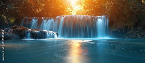 A beautiful waterfall in the forest with blue water and golden trees, sunlight shining through the leaves onto the sparkling river below, creating an enchanting scene of tranquility and beauty. 