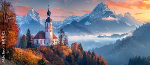A picturesque autumn landscape featuring the white alps mountains, a church nestled in an ancient forest with colorful trees and mist rising from its spires, bathed by golden sunlight