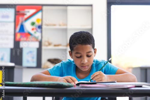 Biracial boy focused on his schoolwork in the classroom at school