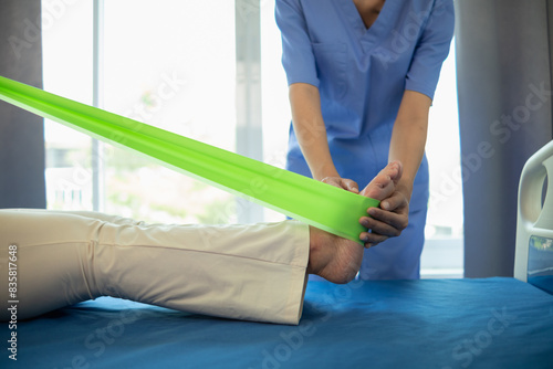 female doctor using elastic bands help patient regain muscle movement after recuperating from muscle injury and wants rehabilitate her be able use her normal daily life by practicing physical therapy
