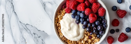 Bowl of muesli with yogurt and berries on a marble background