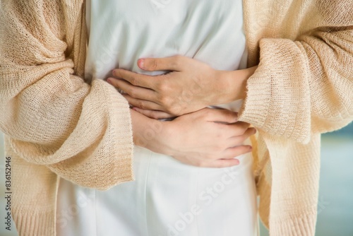 Hungry Asian woman with stomach ache, concept image of menstrual period cramp, abdominal pain, food poisoning, gastritis