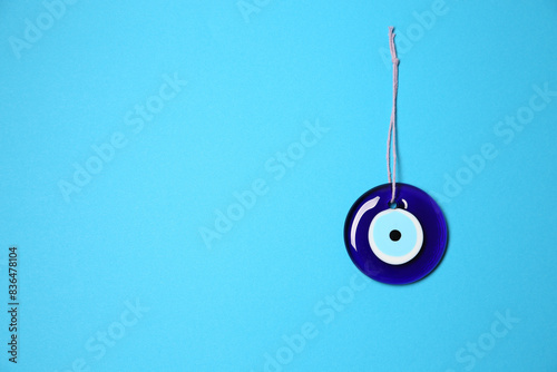 Evil eye amulet on light blue background, top view. Space for text