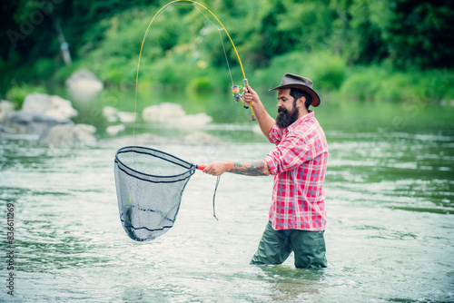 Catching trout fish in net. Fisherman man on river or lake with fishing rod.
