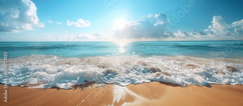 A serene beach scene with sunlit sand and gentle ocean waves. The sky is partly cloudy, adding to the overall calm and peaceful feeling