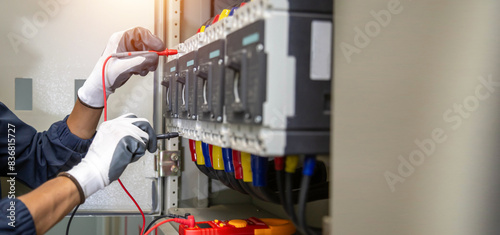 Electrician engineer uses a multimeter to test the electrical installation and power line current in an electrical system control cabinet. 