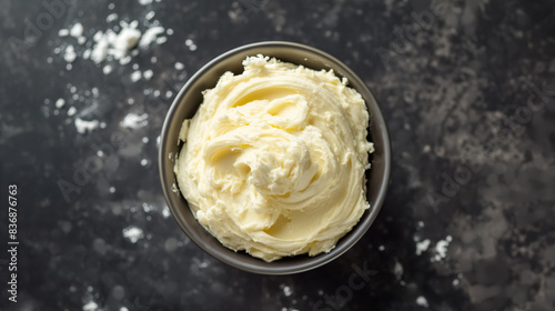 Bowl of creamy, smooth butter on a dark marbled surface, creating a rich and appetizing visual with a soft, whipped texture.