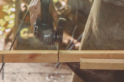 Hand of a craftsman with a circular saw sawing wooden blocks in an outdoor workshop. Close-up